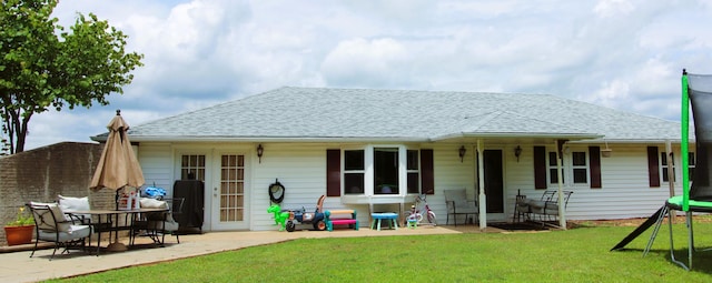 rear view of property featuring a yard, a patio, and a trampoline