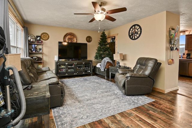 living room featuring dark hardwood / wood-style floors, ceiling fan, and a textured ceiling