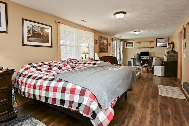 bedroom with dark hardwood / wood-style floors and a textured ceiling