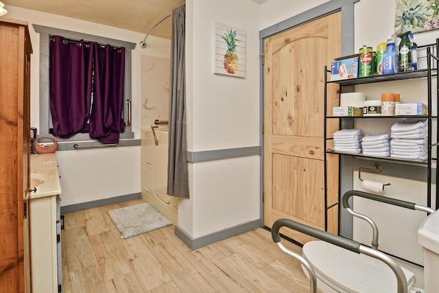 bathroom featuring hardwood / wood-style floors, toilet, a shower, and a textured ceiling