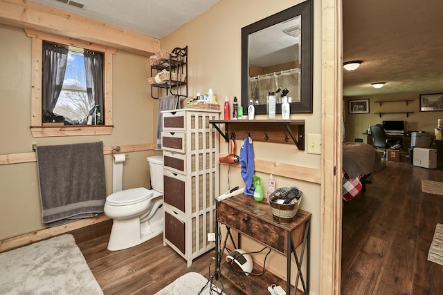 bathroom featuring toilet, wood-type flooring, and a textured ceiling