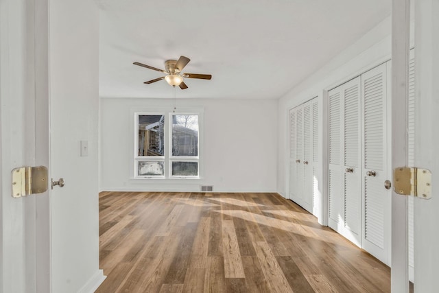 213 Mill St, Anderson, MO 64831 - unfurnished bedroom featuring multiple closets, wood finished floors, baseboards, and a ceiling fan