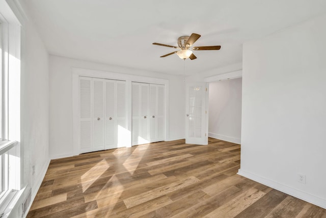 213 Mill St, Anderson, MO 64831 - unfurnished bedroom featuring multiple closets, baseboards, wood finished floors, and ceiling fan