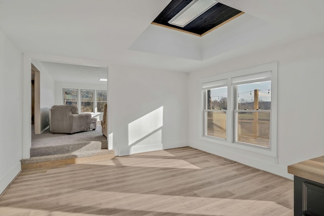 213 Mill St, Anderson, MO 64831 - unfurnished living room with light wood-style flooring, a tray ceiling, and baseboards