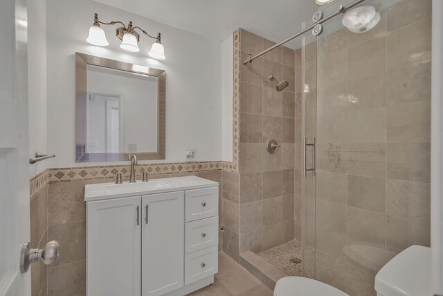 213 Mill St, Anderson, MO 64831 - bathroom featuring tile walls, toilet, a shower stall, vanity, and a wainscoted wall