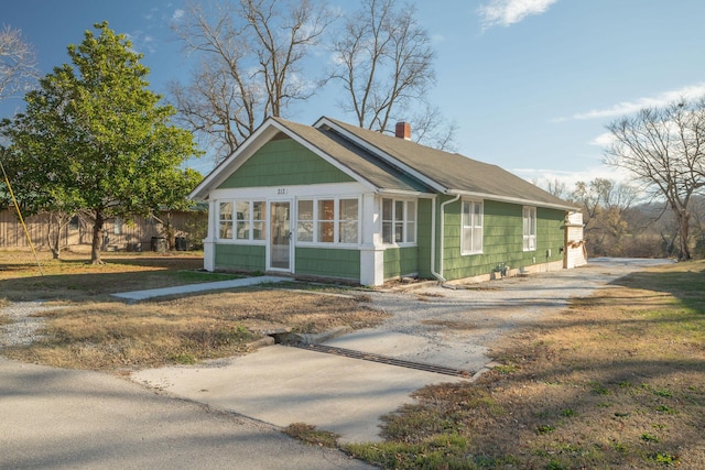 213 Mill St, Anderson, MO 64831 - view of front of home with a chimney, a sunroom, driveway, and roof with shingles