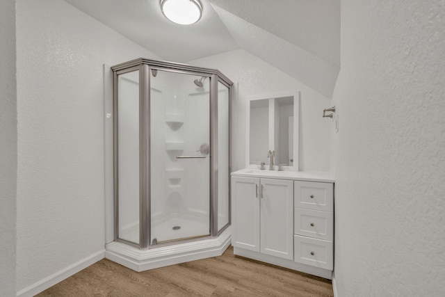 213 Mill St, Anderson, MO 64831 - full bathroom featuring a shower stall, a textured wall, wood finished floors, vanity, and vaulted ceiling