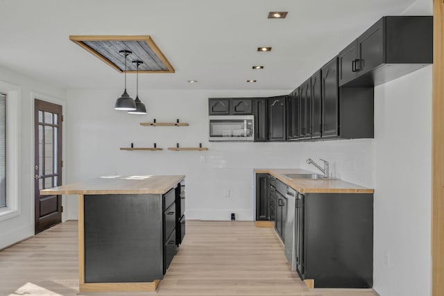 213 Mill St, Anderson, MO 64831 - kitchen featuring stainless steel microwave, a sink, dark cabinetry, light wood-style floors, and backsplash