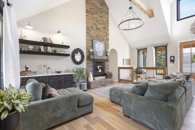 living room featuring light hardwood / wood-style floors, high vaulted ceiling, and a stone fireplace