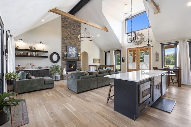 kitchen with a center island with sink, light hardwood / wood-style floors, high vaulted ceiling, and pendant lighting