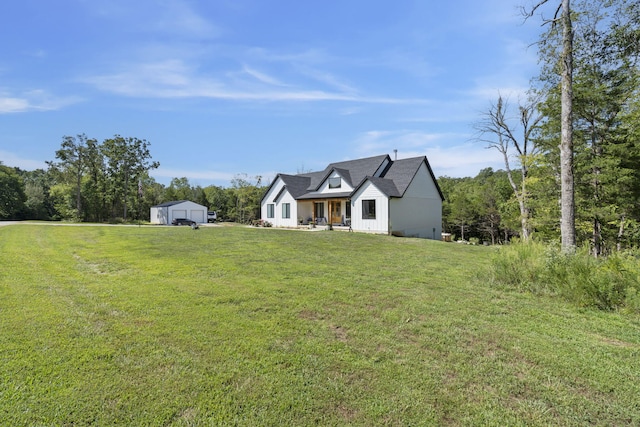 view of front of house with a garage, covered porch, an outbuilding, and a front lawn