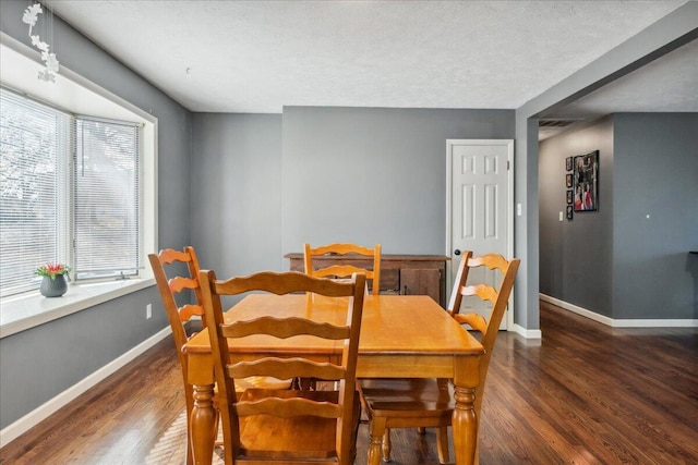 dining room with dark wood-type flooring and a textured ceiling