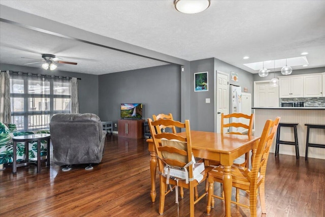 dining area featuring dark wood-type flooring, ceiling fan, and a textured ceiling