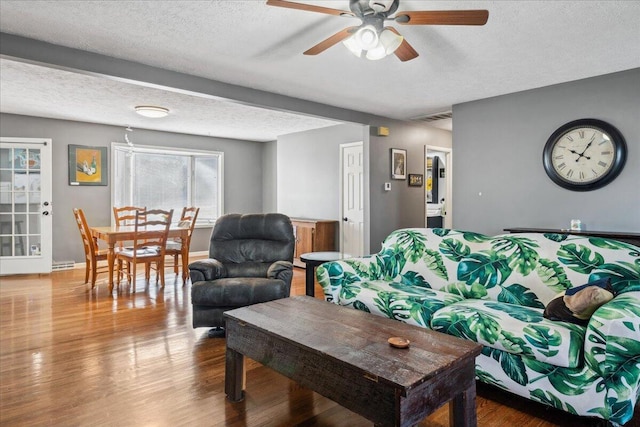 living room featuring ceiling fan, wood-type flooring, and a textured ceiling