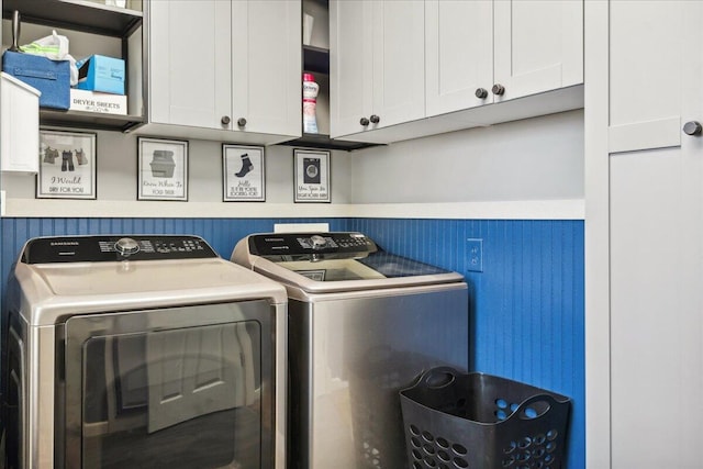 laundry area with separate washer and dryer and cabinets