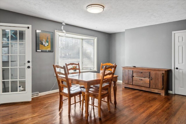 dining room with dark wood-type flooring and a textured ceiling