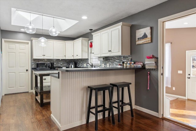 kitchen with pendant lighting, kitchen peninsula, a breakfast bar area, and white cabinets