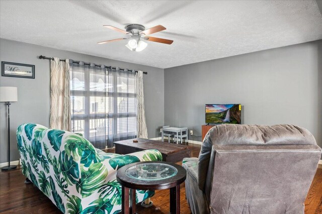 living room featuring ceiling fan, dark hardwood / wood-style flooring, and a textured ceiling