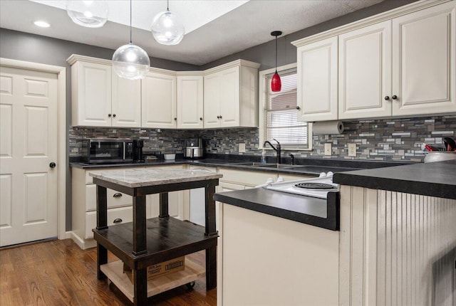 kitchen featuring dark wood-type flooring, sink, tasteful backsplash, pendant lighting, and white cabinets