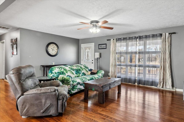 living room with ceiling fan, wood-type flooring, and a textured ceiling