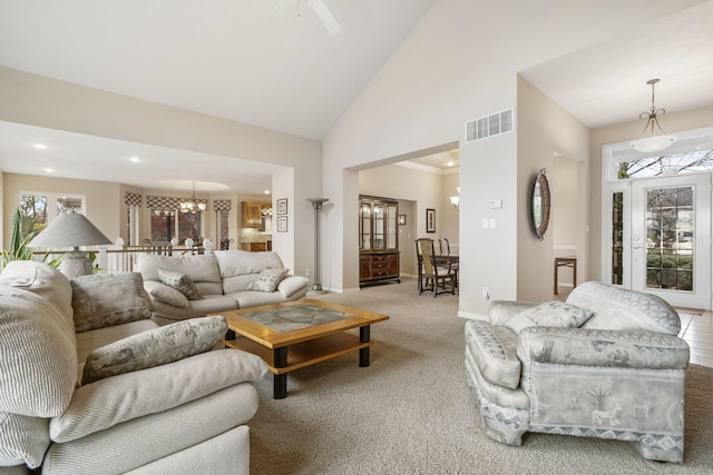 carpeted living room featuring high vaulted ceiling and a notable chandelier