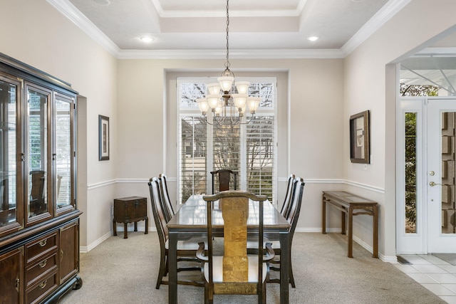 carpeted dining area featuring a tray ceiling, an inviting chandelier, a wealth of natural light, and crown molding