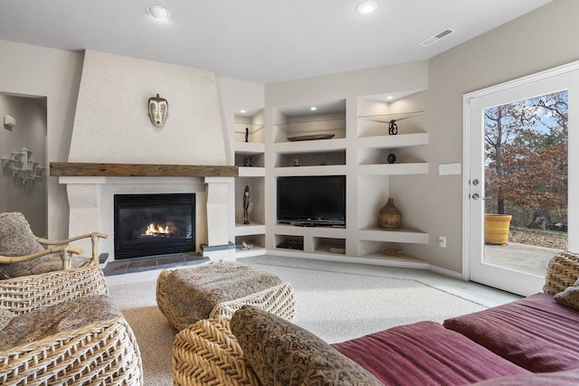 living room featuring a fireplace, light carpet, and built in shelves