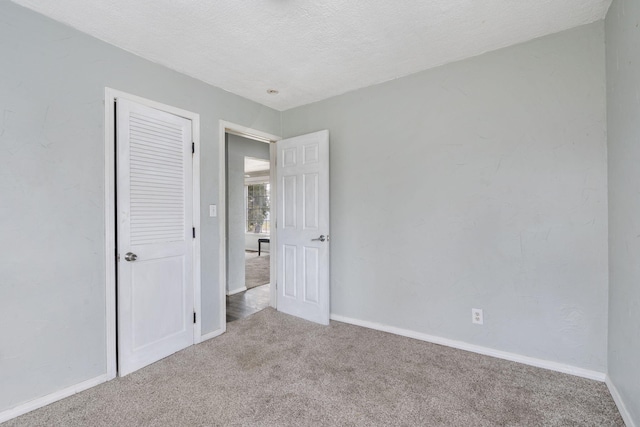 unfurnished bedroom with carpet flooring, a closet, and a textured ceiling