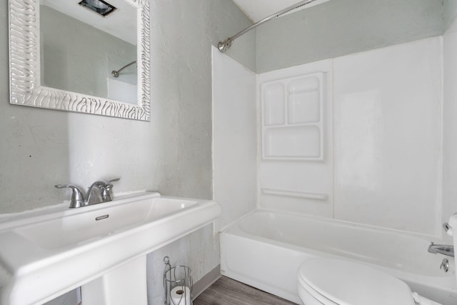 full bathroom with washtub / shower combination, wood-type flooring, toilet, and sink