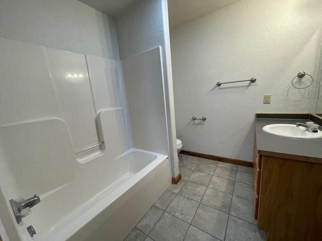 full bathroom with tile patterned floors, shower / bathing tub combination, vanity, and toilet