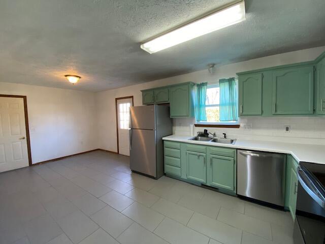 kitchen featuring appliances with stainless steel finishes, green cabinetry, and sink