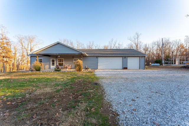 ranch-style house featuring covered porch, a front yard, and a garage