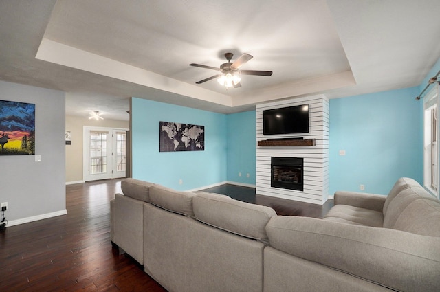 living room featuring dark hardwood / wood-style flooring, a tray ceiling, and a wealth of natural light