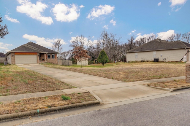 exterior space featuring central AC unit, a garage, and a front yard