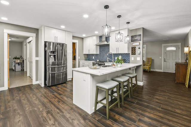 kitchen featuring dark hardwood / wood-style floors, white cabinetry, kitchen peninsula, and stainless steel refrigerator with ice dispenser