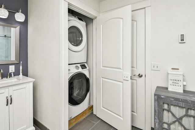 laundry room with sink, stacked washing maching and dryer, and dark tile patterned flooring