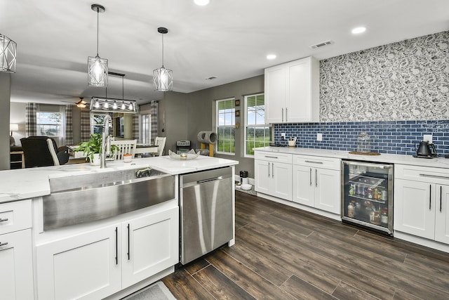 kitchen with dishwasher, dark wood-type flooring, white cabinets, hanging light fixtures, and beverage cooler