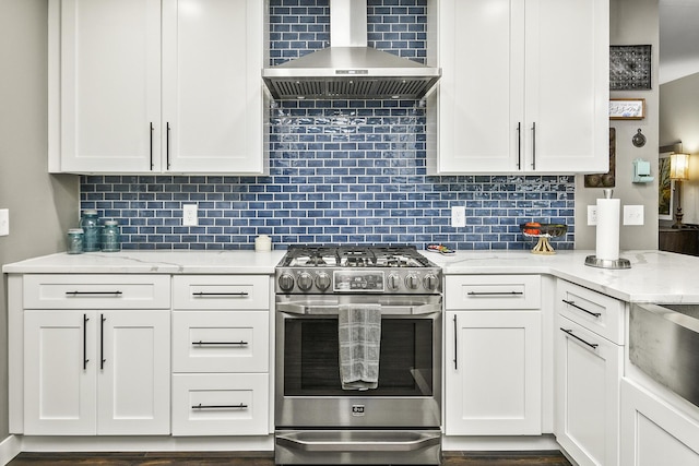 kitchen featuring white cabinets, high end stove, tasteful backsplash, and wall chimney exhaust hood