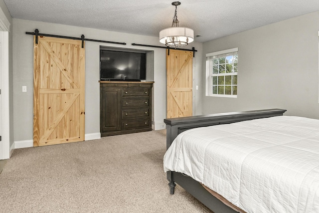 carpeted bedroom with a textured ceiling and a barn door