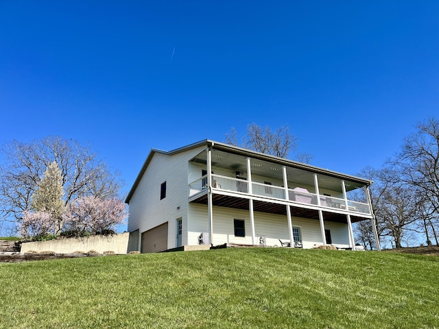 rear view of property featuring a lawn, a garage, and a balcony