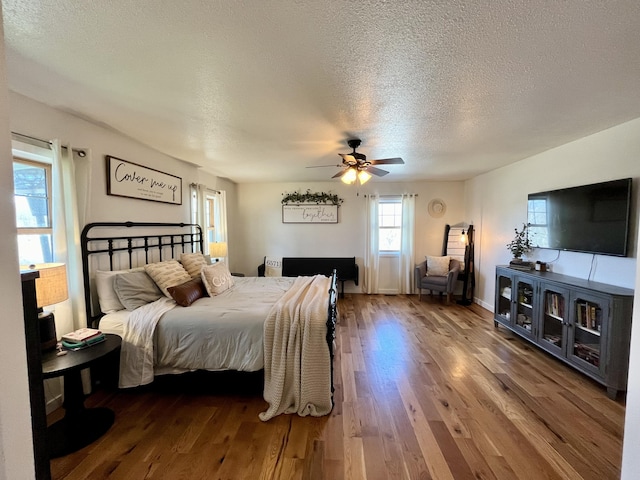 bedroom with a textured ceiling, ceiling fan, and wood finished floors