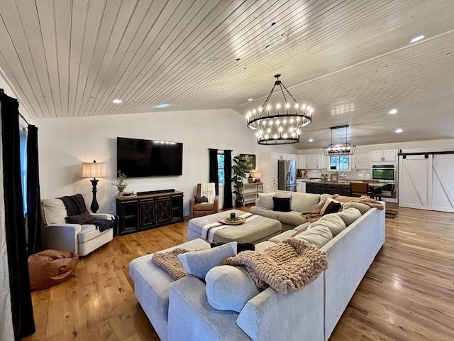 living room with light wood-type flooring, vaulted ceiling, a barn door, an inviting chandelier, and wooden ceiling