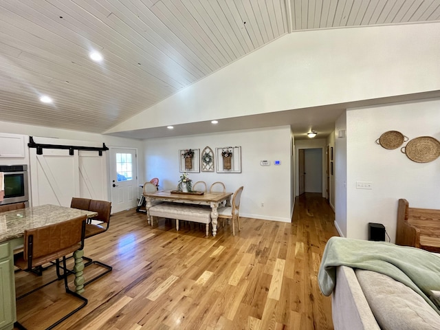 dining space with a barn door, wooden ceiling, high vaulted ceiling, and light hardwood / wood-style floors