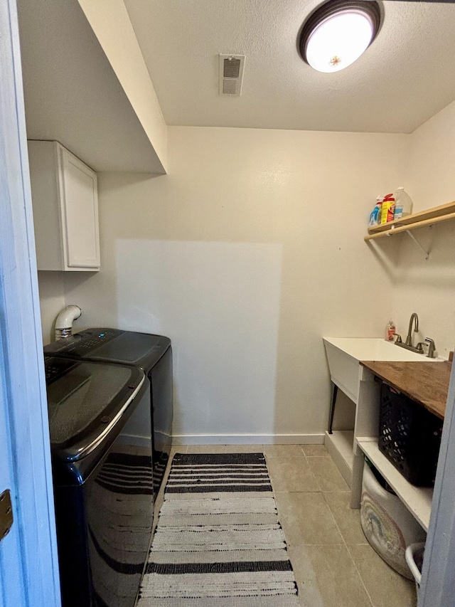 clothes washing area with visible vents, baseboards, washer and dryer, cabinet space, and a textured ceiling