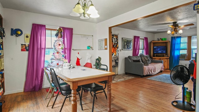 dining space featuring ceiling fan with notable chandelier and hardwood / wood-style flooring