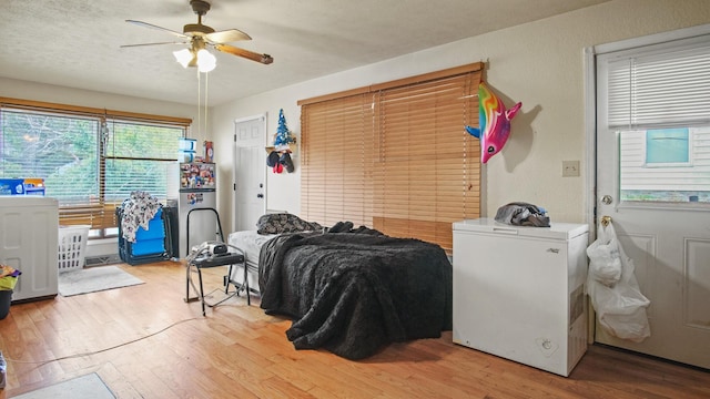 bedroom featuring ceiling fan, light hardwood / wood-style flooring, a textured ceiling, and white refrigerator