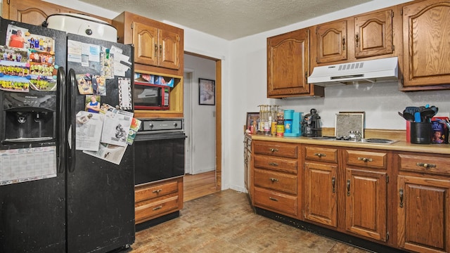 kitchen with black appliances, a textured ceiling, and light hardwood / wood-style flooring