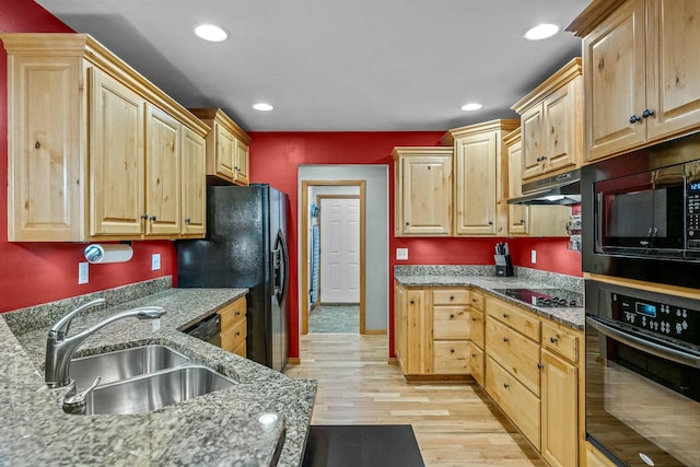 kitchen with black appliances, sink, light brown cabinetry, light hardwood / wood-style floors, and light stone counters