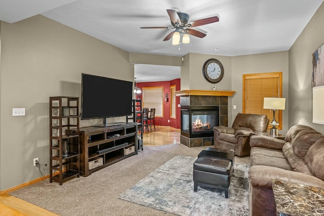 living room with ceiling fan, wood-type flooring, and a tiled fireplace