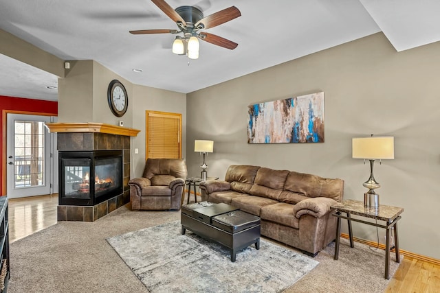 living room featuring hardwood / wood-style flooring, ceiling fan, and a tiled fireplace